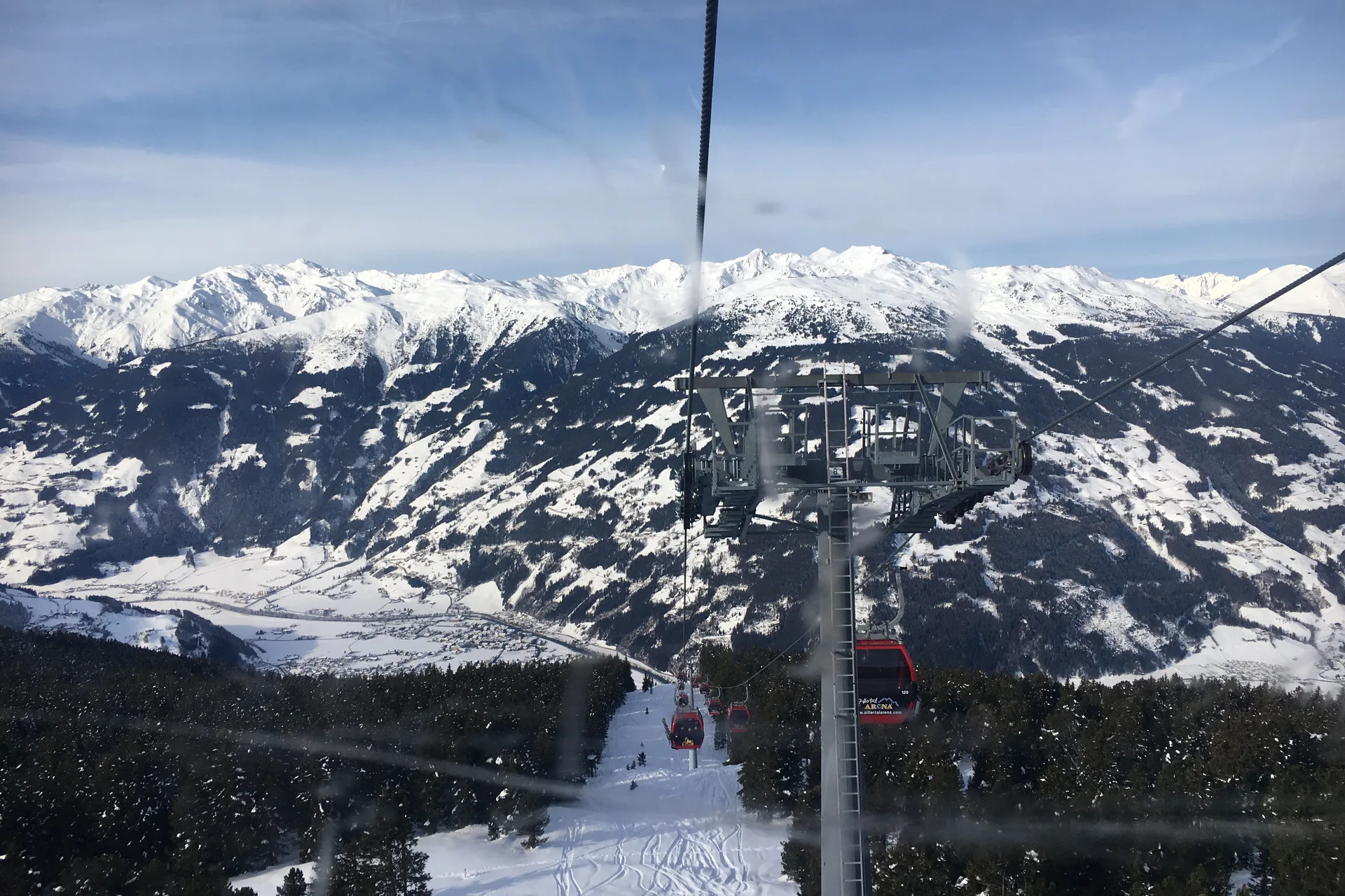 Red Karspitzbahn gondolas above snowy slopes and the valley near Zell am Ziller.